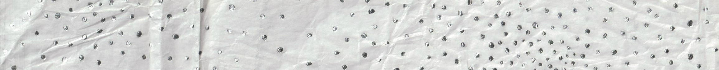 Close-up of a textured tissue paper, white surface with silver dots